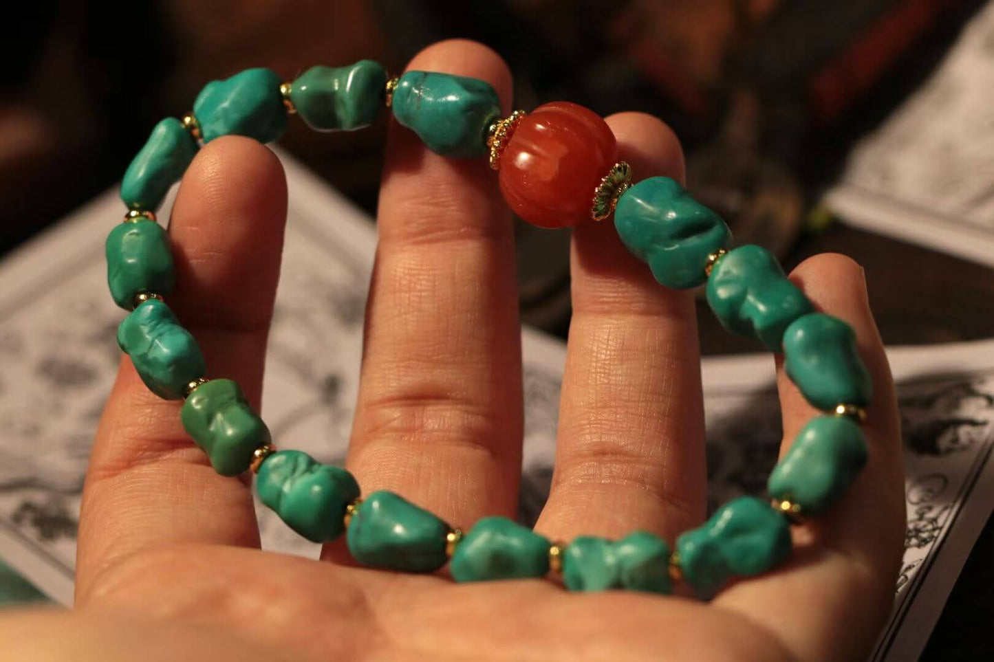 Turquoise bracelet with South Red Agate being held, showcasing vibrant turquoise stones and a red agate centerpiece.